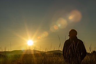 Silhouette of man in field at sunset