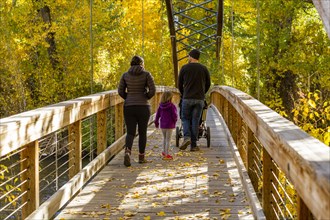 Family crossing bridge in autumn