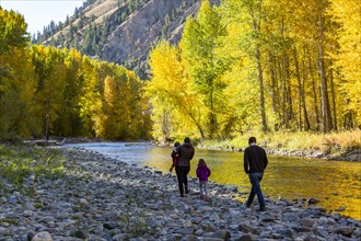 Family admires fall along river in autumn