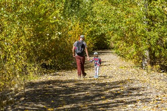 Father and daughter walk rural path in fall