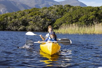 Boy and teenage girl kayaking in lagoon