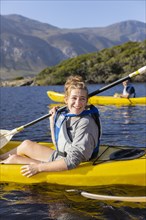 Smiling teenage girl kayaking in lagoon