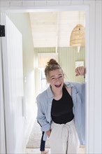Portrait of teenage girl standing in doorway and laughing