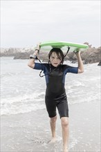 Boy carrying bodyboard on Voelklip beach