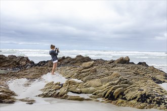 Teenage girl taking photos on Voelklip beach