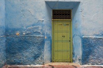 Colorful blue walls and old door in alleyway in medina
