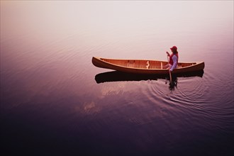 High angle view of woman paddling canoe on Lake Placid at sunrise