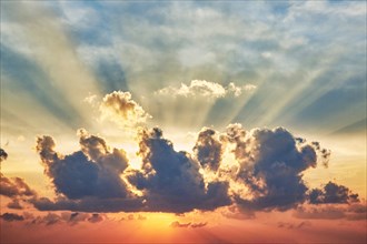 Sun rays above cumulus cloud at sunset