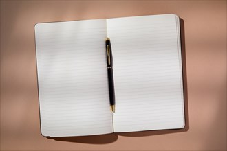 Pen in open notebook on brown background