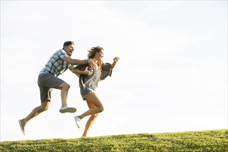 Woman and man running on hill in park