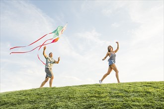 Man and woman flying kite in park