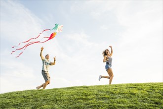 Woman and man flying kite in park