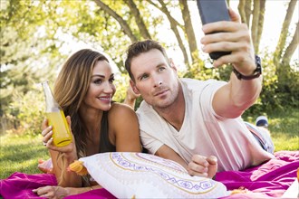 Man taking picture with smart phone at picnic in park