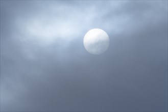 Hazy sun behind wispy clouds