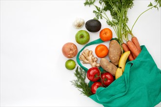 Overhead view of fresh vegetables and fruit in bag against white background