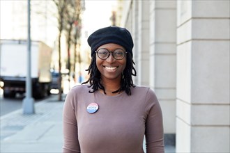 Portrait of smiling woman with Vote button in city