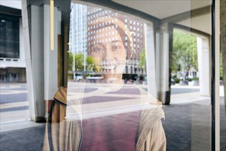 Portrait of smiling woman seen through window in city