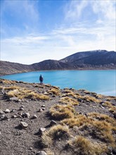 Hiker standing by lake in Volcanic landscape