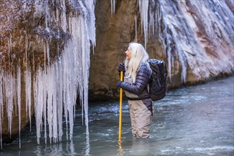 Senior woman looking at icicles while hiking in mountains