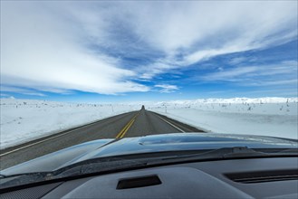 Highway through snow-covered landscape as seen from car