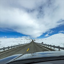 Highway through snow-covered landscape as seen from car