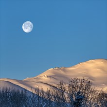 Full moon over snow-covered hills