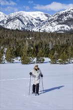 Senior woman wearing snowshoes hiking in mountains