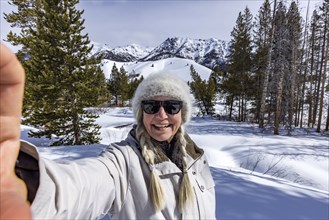 Senior woman taking selfie in snowy mountains