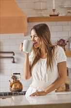 Woman drinking from mug in kitchen