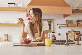 Smiling woman enjoying healthy breakfast in kitchen