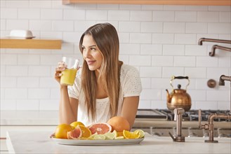 Woman drinking fresh citrus juice in kitchen