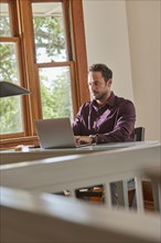Man using laptop at table at home