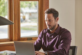 Man using laptop at desk at home