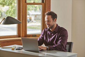 Man using laptop at desk at home