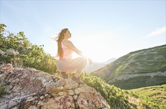 Mid adult woman crouching on rock during hike