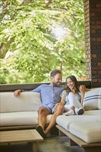 Mid adult couple relaxing on sofa on patio
