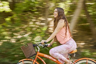 Smiling young woman riding bicycle in park