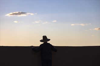 Silhouette of man in hat looking at sunset