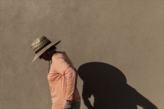 Senior woman in hat casting shadow on wall