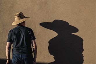 Man in hat casting shadow on wall