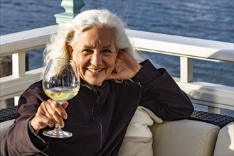 Portrait of smiling senior woman relaxing with glass of wine