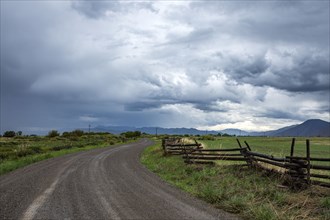 Dramatic clouds above empty road and meadow