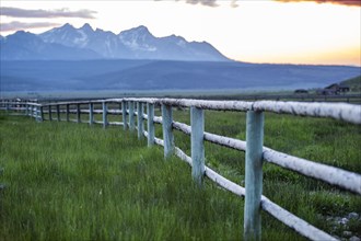 Scenic view of Sawtooth Mountains and meadow with rail fence at sunset
