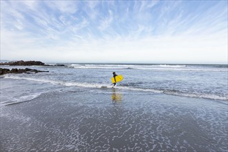 Boy entering Atlantic Ocean with body board