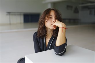 Portrait of young woman looking at camera while sitting in dance studio