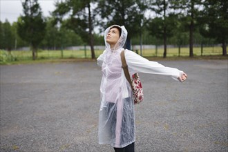 Portrait of young woman with arms outstretched in rain