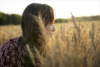 Portrait of young woman looking at agricultural field at sunset