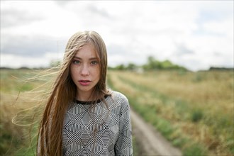 Portrait of young blond woman looking at camera in field