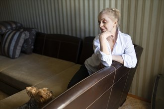 Woman sitting on sofa and looking at Yorkshire terrier