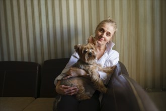 Portrait of woman holding Yorkshire terrier in living room
